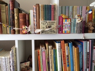 A white bookshelf with mostly children's books, spine out